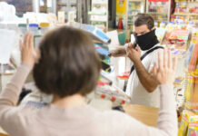 A masked individual threatening a store clerk during a robbery