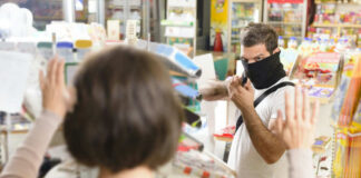 A masked individual threatening a store clerk during a robbery