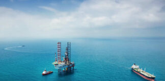 Oil rig surrounded by ships in the ocean.