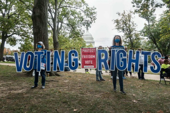 People holding Voting Rights sign near the Capitol building.