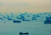 Numerous cargo ships scattered across a hazy ocean