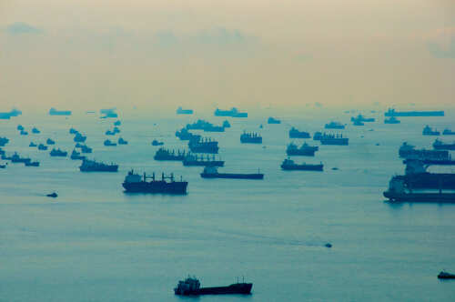 Numerous cargo ships scattered across a hazy ocean