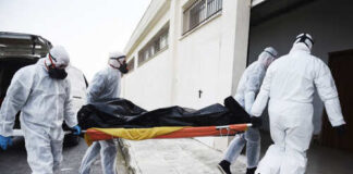 Emergency responders in hazmat suits carrying a body on a stretcher