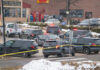 Multiple police vehicles at a scene with caution tape and emergency lights activated