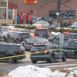 Guns Seized At Omar-Linked Apartment Multiple police vehicles at a scene with caution tape and emergency lights activated