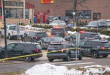 Guns Seized At Omar-Linked Apartment Multiple police vehicles at a scene with caution tape and emergency lights activated