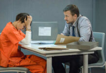 Clown Mask Murder Shocker A detective interrogating a prisoner in an orange jumpsuit at a table