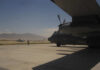 Military aircraft on an airfield with a crew member in the foreground