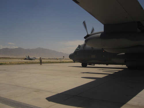 Military aircraft on an airfield with a crew member in the foreground