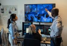 Three professionals analyzing security footage on multiple screens