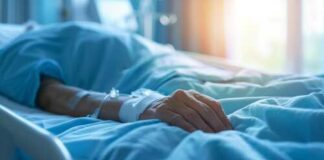 A patient's hand resting on a hospital bed with an IV line attached