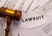 A wooden gavel next to a torn paper with the word 'LAWSUIT'