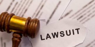 A wooden gavel next to a torn paper with the word 'LAWSUIT'