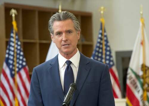 Turlock,,Ca,-,Jan,6,,2025:,Ca,Governor,Gavin,Newsom A government official speaking at a podium with flags in the background
