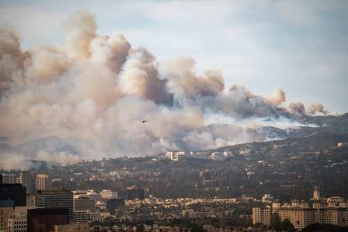 Wildfire,In,Pacific,Palisades,,Los,Angeles,,January,8,,2025,,Towards A wildfire producing thick smoke over a city landscape with a helicopter in the sky