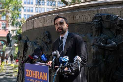 A man giving a speech at a podium in a city park