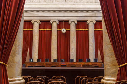 Interior view of a courtroom with red curtains and marble columns