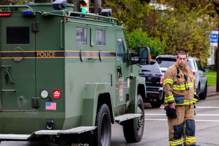 1213929463 Firefighter standing beside green police armored vehicle