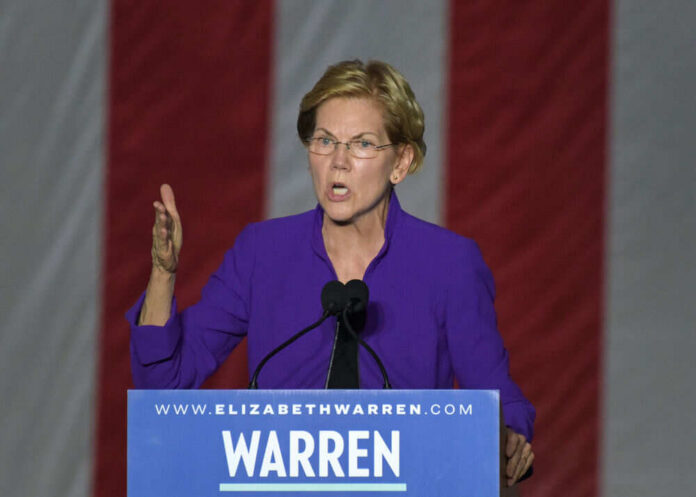 Person speaking at podium with hand raised.