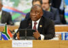Man speaking at conference with South African flag