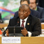 Man speaking at conference with South African flag