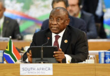 Man speaking at conference with South African flag