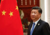 A political leader standing beside the Chinese national flag