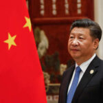 A political leader standing beside the Chinese national flag