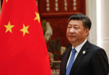 A political leader standing beside the Chinese national flag