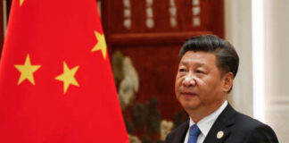 A political leader standing beside the Chinese national flag