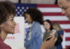 California Drops ID — What Could Go Wrong? A woman showing her ID to a man at a voting station