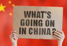 Mortgage Math Shock: 40 Year Mortgage, Still No Buyers Hands holding a cardboard sign with the text 'What's going on in China?' against a red background with stars