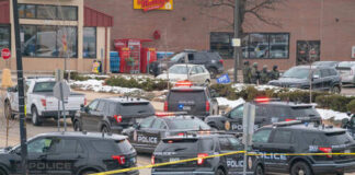 Multiple police vehicles at a scene with caution tape and emergency lights activated