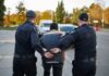 Two police officers escorting a handcuffed suspect