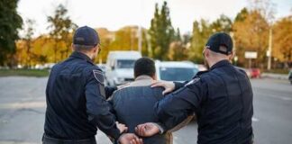 Two police officers escorting a handcuffed suspect