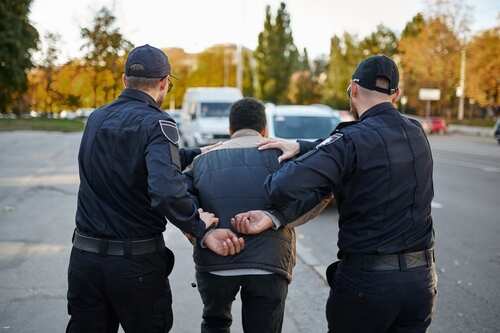 Two,Male,Police,Officers,Arrest,Young,Man Two police officers escorting a handcuffed suspect