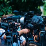 Delete-And-Flip Stuns Congress TV news cameras crowding together at an outdoor event