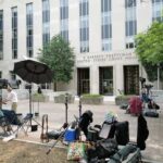 Media equipment and journalists outside a courthouse