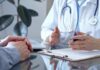 $200B Health Fight Explodes A doctor discussing with a patient over a clipboard in a medical office