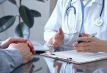$200B Health Fight Explodes A doctor discussing with a patient over a clipboard in a medical office