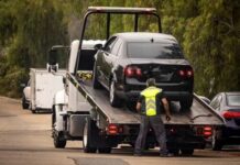 A tow truck lifting a black car onto its flatbed