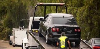 A tow truck lifting a black car onto its flatbed