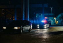 Hit-And-Run Horror: Teen Dead, Suspect Vanishes A police car with flashing lights parked next to a dark vehicle in a dimly lit urban area