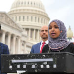 Three people speaking in front of US Capitol building