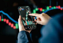 Hands using smartphone displaying stock market data