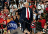 Trump Warns: China Grabs Our Data Hubs Man pointing in front of cheering crowd at rally.