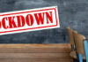 A sign reading 'LOCKDOWN' hanging in a classroom with empty chairs