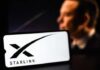 A smartphone displaying the Starlink logo with a blurred figure in the background
