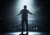 Silhouette of a speaker on stage with an audience in the background