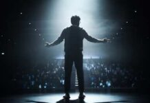 Silhouette of a speaker on stage with an audience in the background